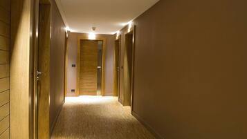 A hallway with wooden walls and doors, leading to a room with a wooden door.