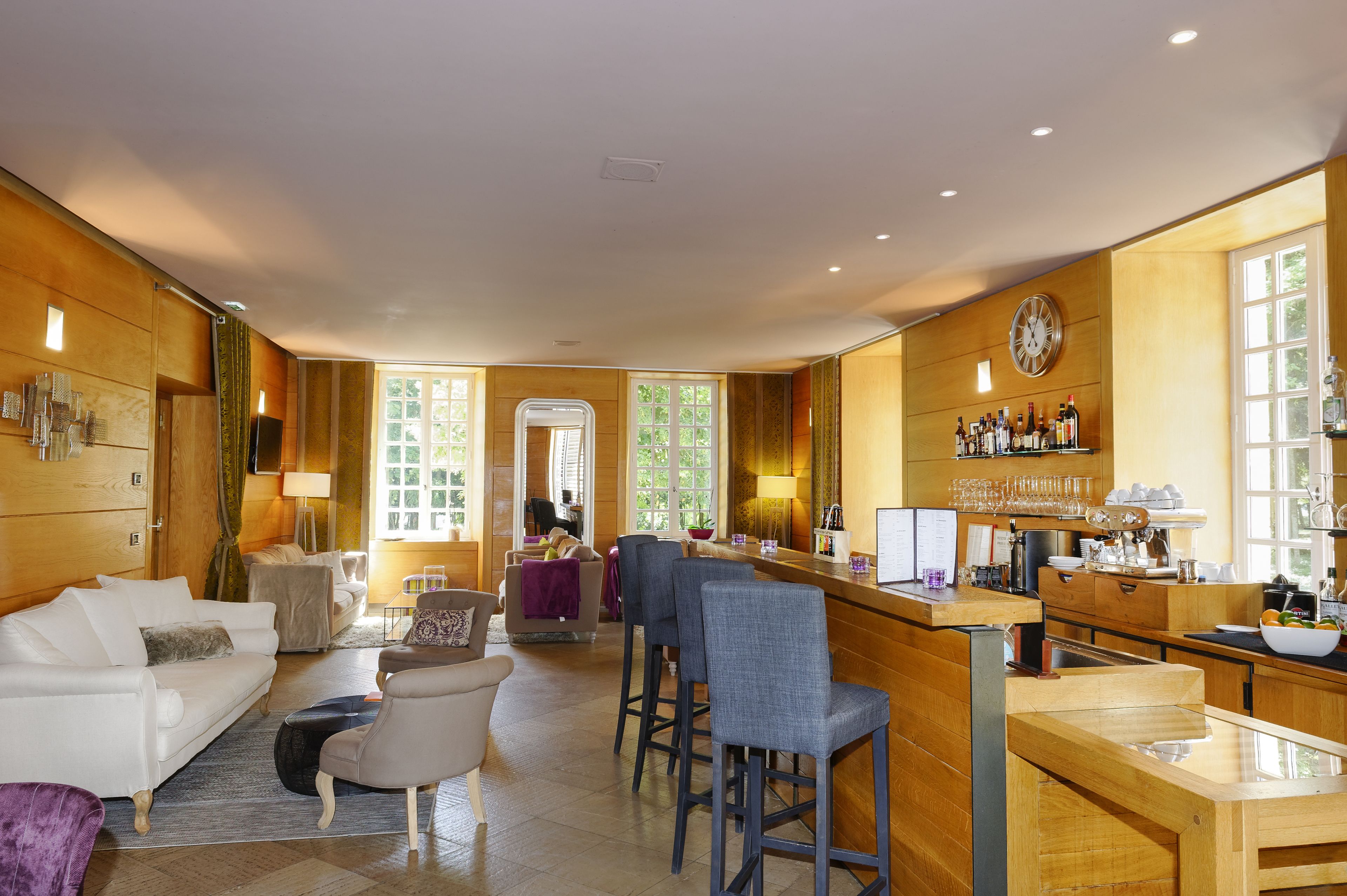 A spacious living area with a bar, seating, and a view of the outdoors.