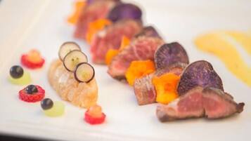 A plate of food with various items including slices of meat, fruit, and small round objects.