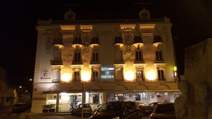 A historic hotel with a classic facade, illuminated signage, and a ground-level restaurant. - Hôtel des Bourbons (Montlucon)
