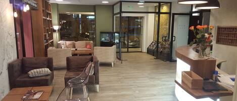 A hotel lobby with seating areas, a reception desk, and a visible restaurant sign.
