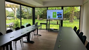 A conference room with a large table, chairs, and a presentation screen.