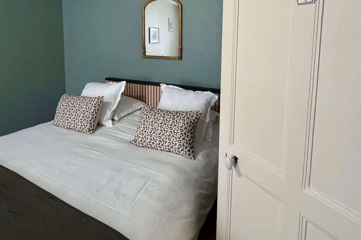 Quarto com cama, almofadas, espelho e porta.