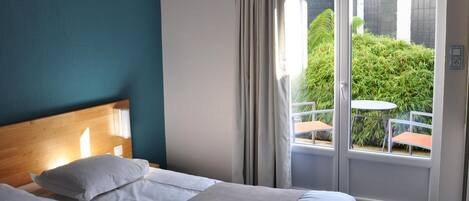 Ein Hotelzimmer mit Bett, Blick ins Freie und einem Balkon mit Tisch und Stühlen.