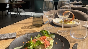 A dining table with a plate of food, wine glasses, and cutlery.