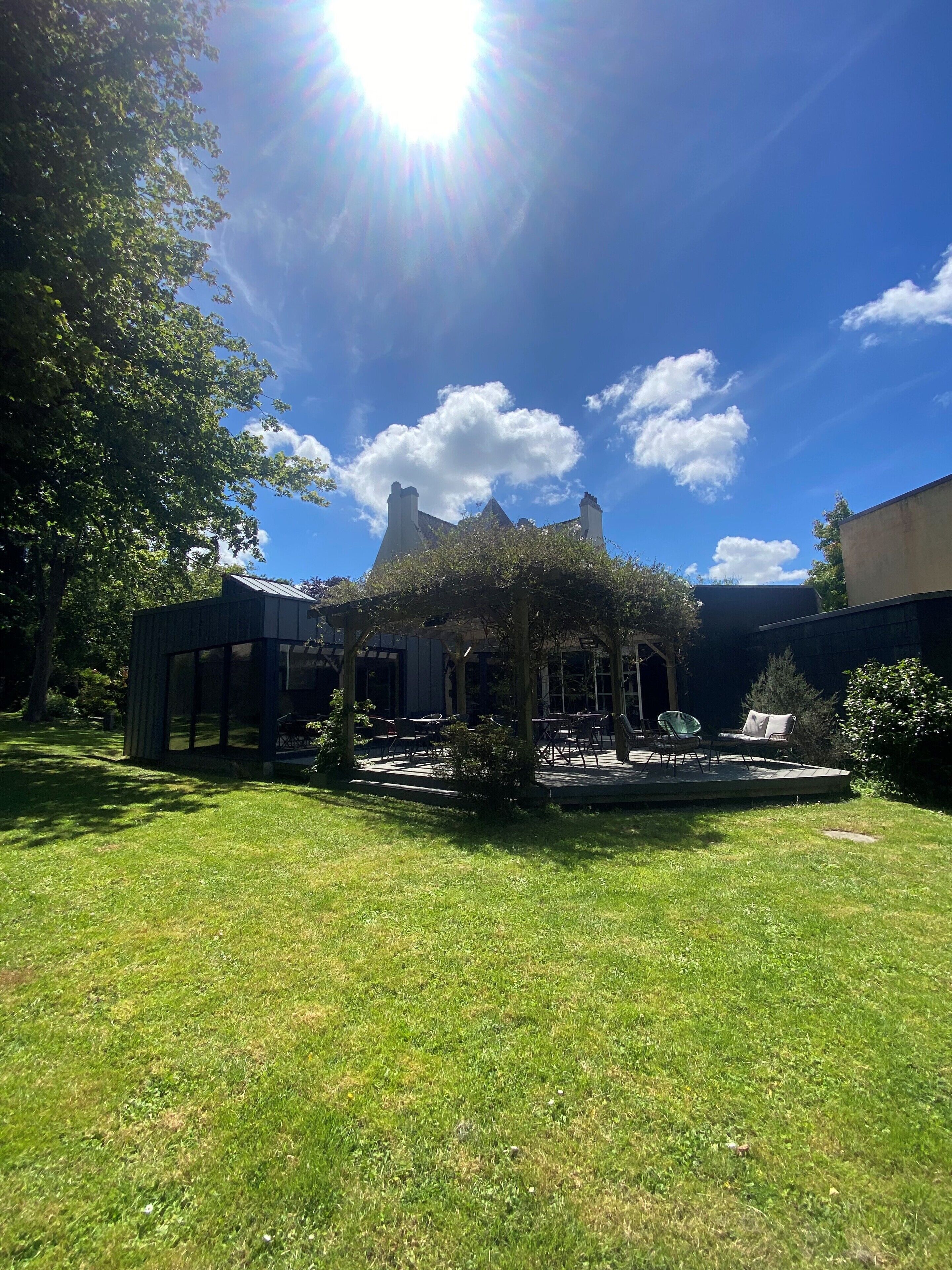 A courtyard with a pergola, outdoor seating, and a building with a distinctive roof in the background.