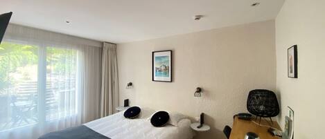 A hotel room with a bed, a desk, a chair, a coffee maker, and a picture on the wall.