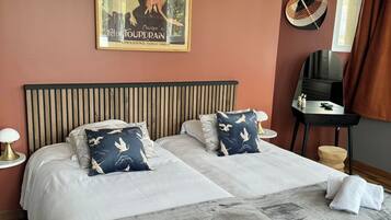 Una cama doble con dos almohadas, una mesita de noche con lámpara, un espejo y un cartel en la pared.