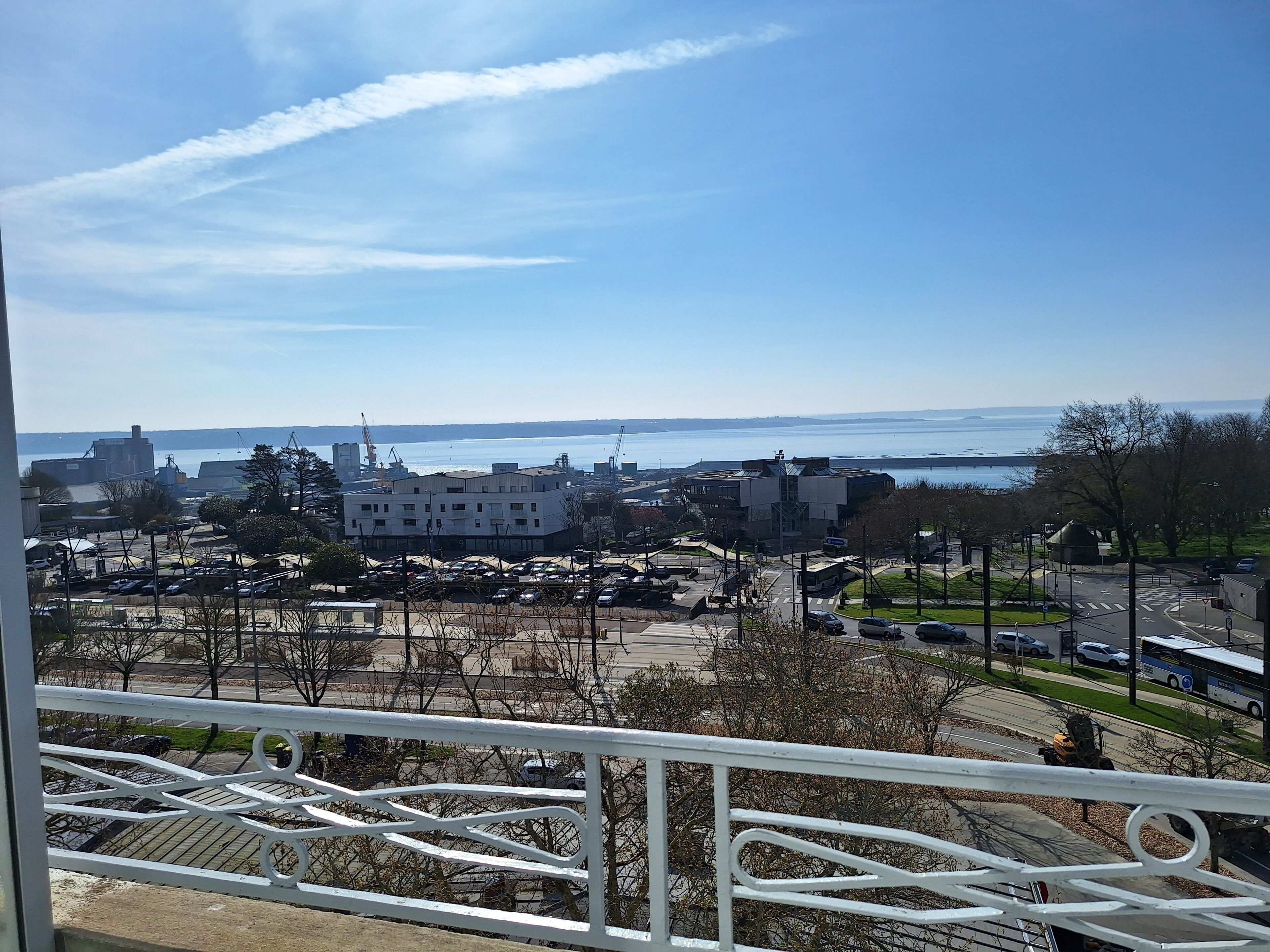 A view of a coastal area with buildings, a parking lot, and a clear sky.