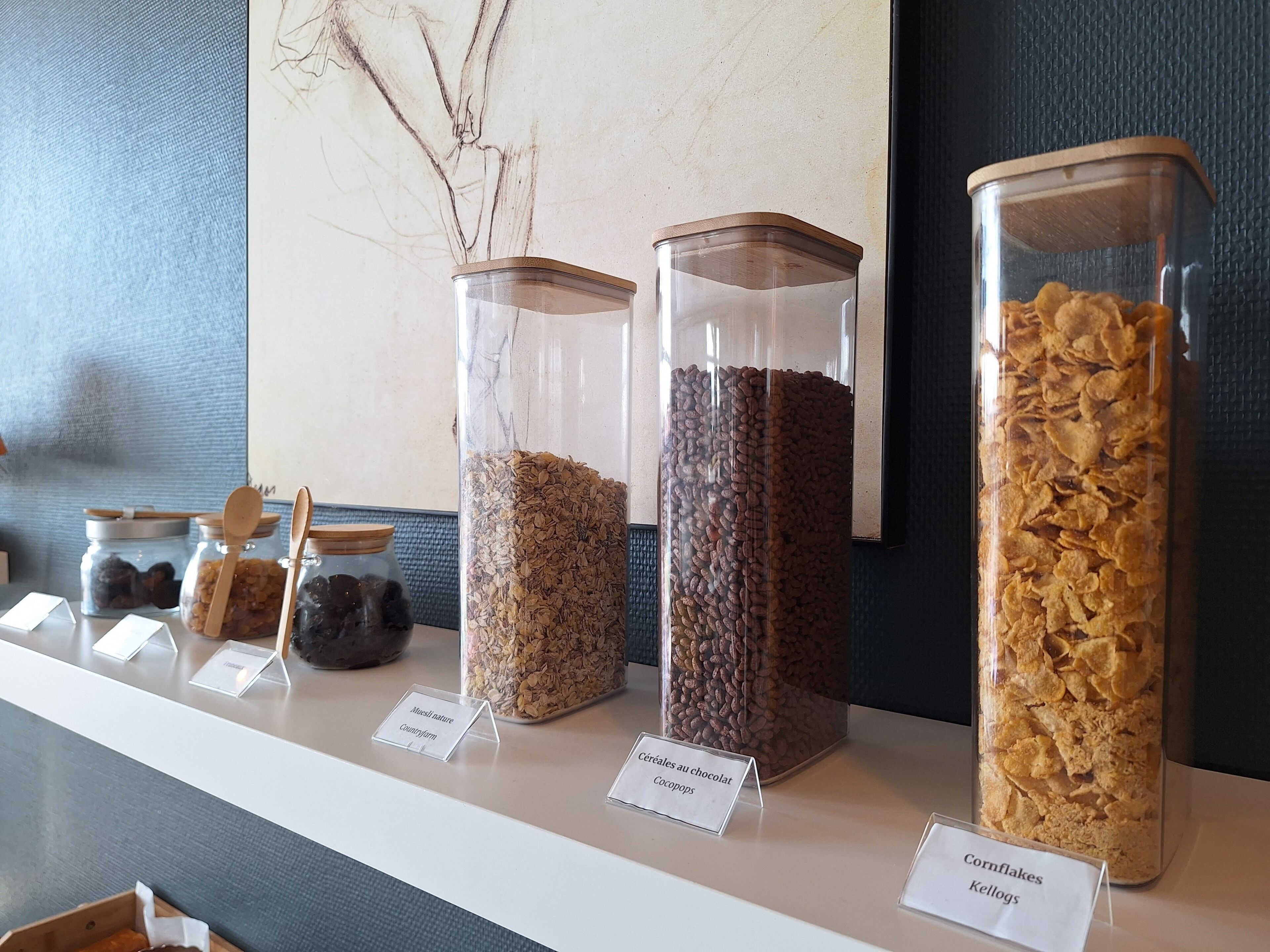 A display of various cereals in clear containers with labels.