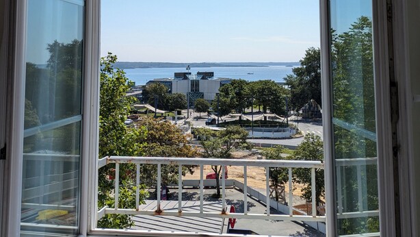 Vista desde una ventana con cielo despejado, un edificio y una masa de agua.