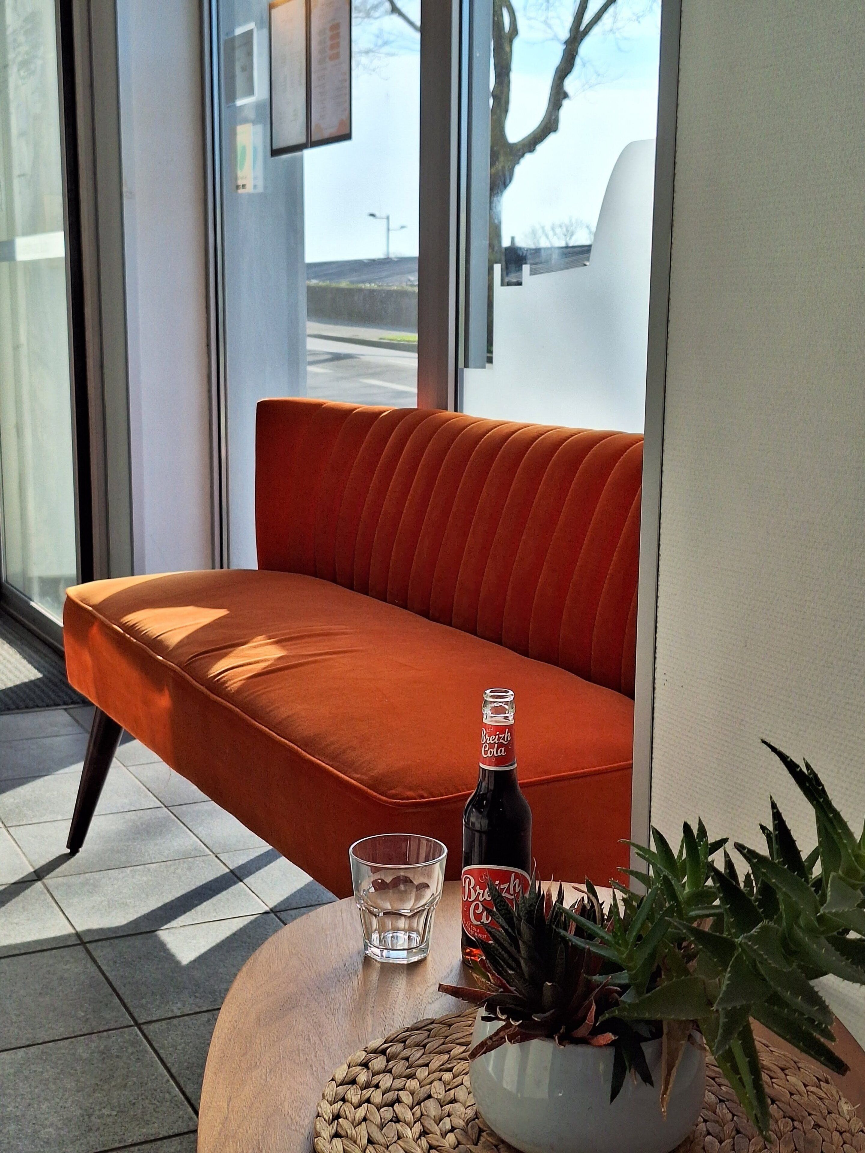 Ein modernes Interieur mit einer Couch, einer Bierflasche, einem Glas und einem Blumentopf auf einem runden Tisch.
