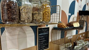 Una vitrina de panadería con botes de cereales y un menú en una pizarra que anuncia productos como brioche y croissants.