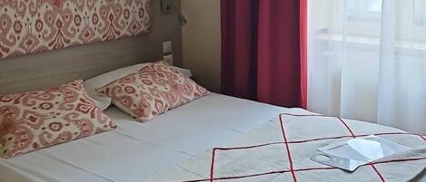 A neatly made bed with patterned pillows, a headboard, and a bedside table with a lamp.