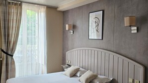 Una habitación de hotel con una cama grande, una mesita de noche, una silla y una ventana con cortinas.