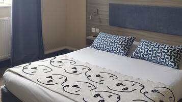 Een hotelkamer met een bed, hoofdeinde, raam met gordijnen en wanddecoratie.