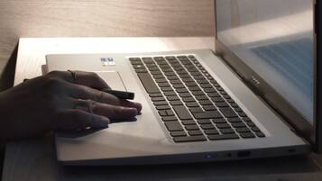 Una laptop sobre un escritorio, con una mano escribiendo en el teclado.