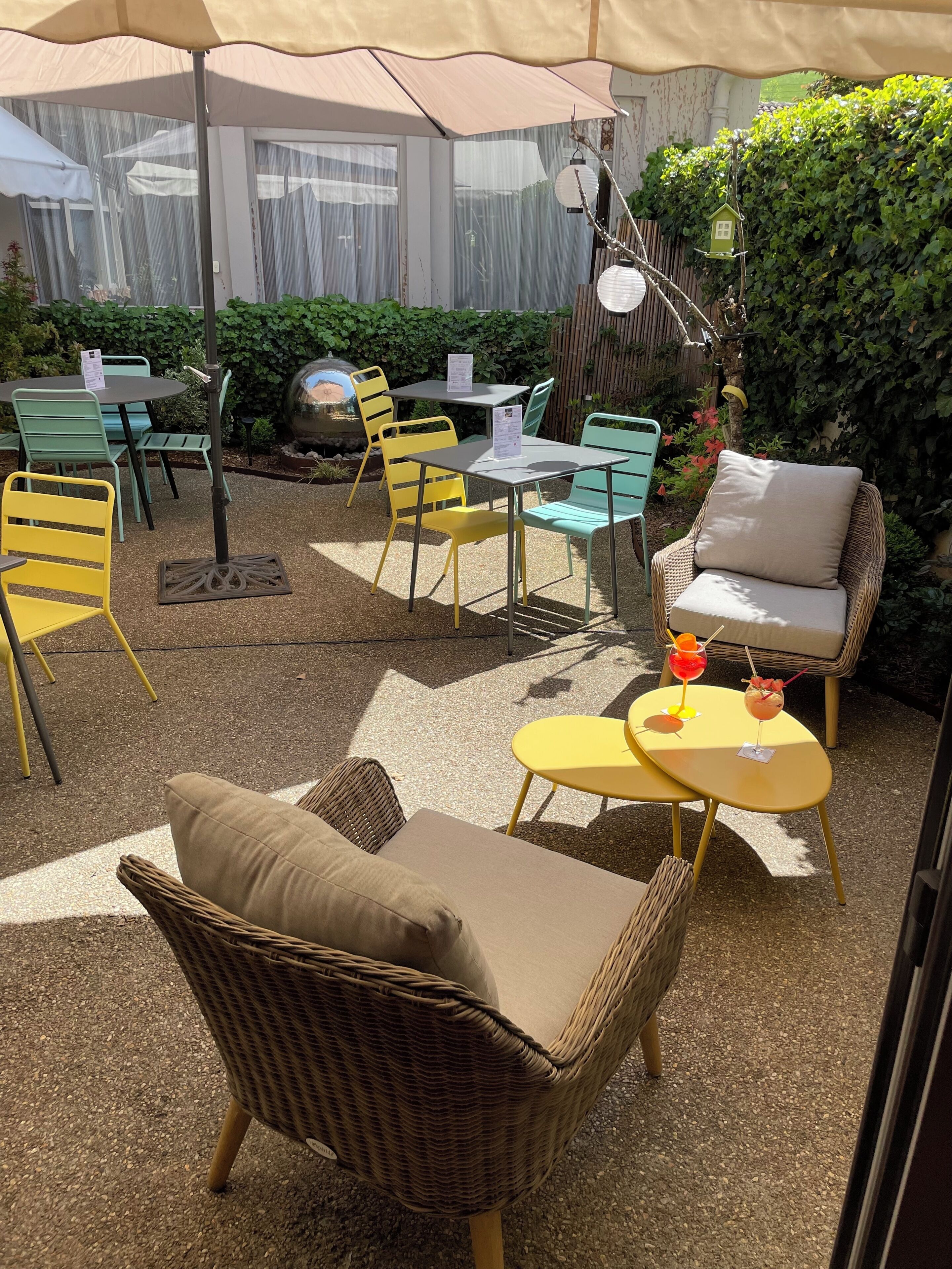 Un área de estar al aire libre con mobiliario de mimbre, una mesita con bebidas y un comedero decorativo.