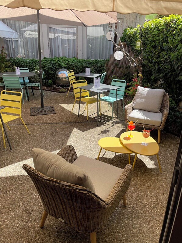 An outdoor seating area with wicker furniture, a small table with drinks, and a decorative birdhouse.