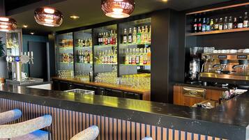 Zona de bar con mostrador, asientos y una variedad de botellas y vasos.