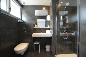 A modern bathroom with a toilet, sink, and shower.