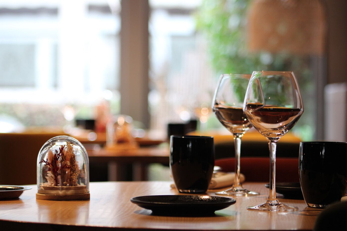 Et bord med to vinglas, et glas vand og en pynteting på et træbord i en restaurant.