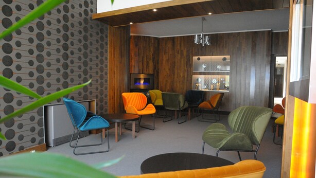 A modern interior with a fireplace, multiple seating areas, and a kitchen in the background.