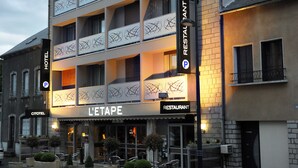 A multi-story hotel with balconies, a restaurant, and a parking sign.