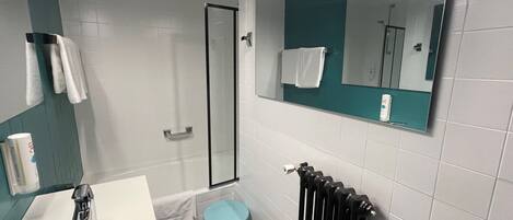 A bathroom with a white sink, a blue toilet, a glass shower enclosure, and a mirror with a teal frame.