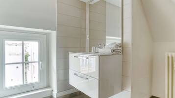 Une salle de bain moderne avec un grand miroir, un lavabo encastré et une fenêtre.