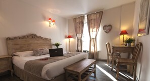 Een slaapkamer met een houten bed, een bureau met stoel, een laptop en een hartvormige decoratie aan de muur.