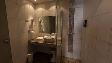 A modern bathroom with a glass-enclosed shower, a sink with a mirror, and a toilet.