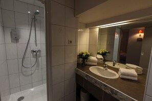 Une salle de bain moderne équipée d’une douche, d’un lavabo et d’un miroir.