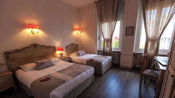 A hotel room with two beds, a desk, and a chair.