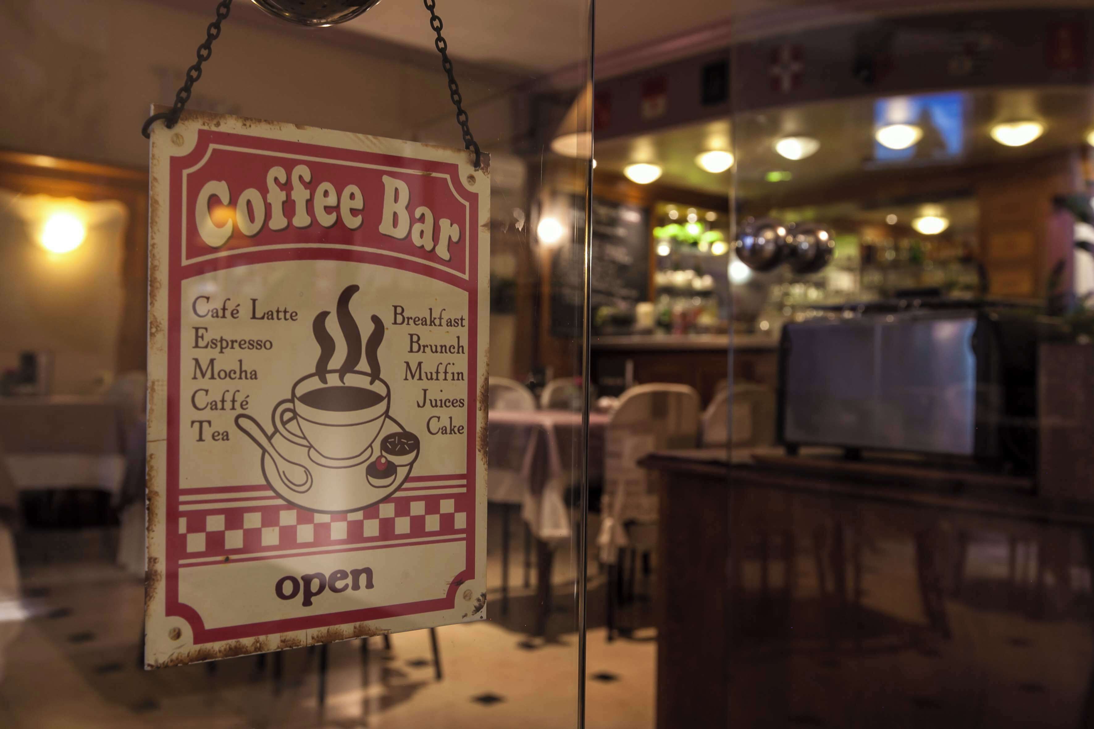 Señal de una cafetería con una lista de bebidas y alimentos.