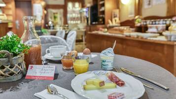 A breakfast setting with a plate of food, a glass of orange juice, a bottle of milk, and a menu card.