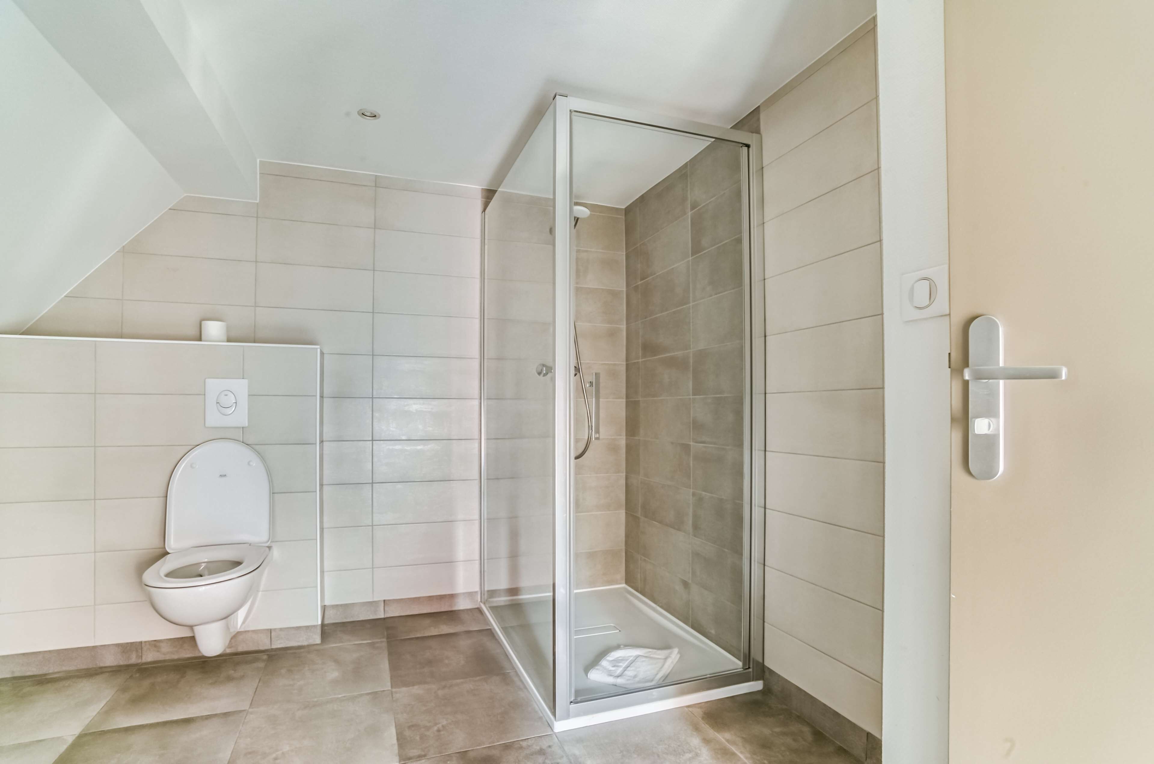 Une salle de bain moderne dotée d’une douche à parois de verre, de toilettes et d’un porte-serviettes.