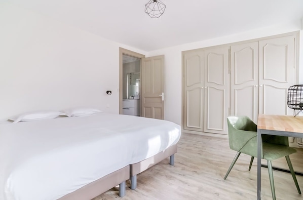 Un dormitorio con cama, una mesa de madera, una silla verde y un armario.