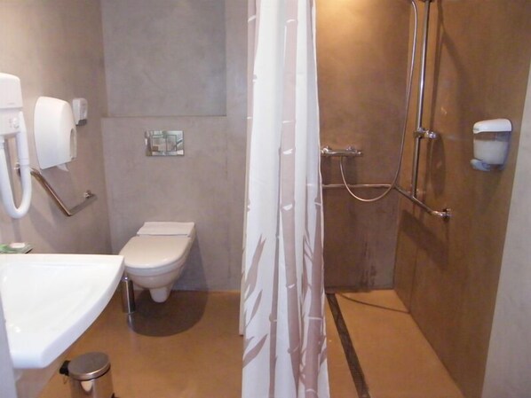A small bathroom with a toilet, sink, and shower.