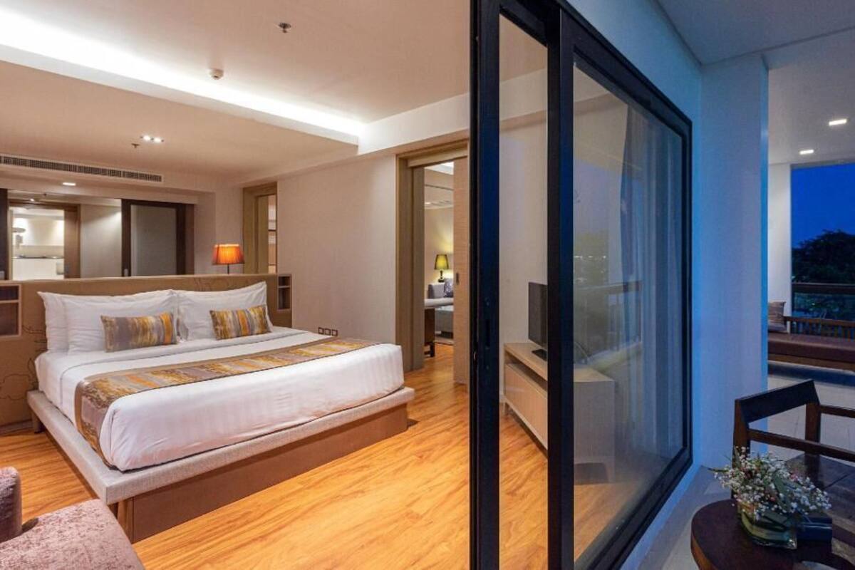 Una habitación de hotel moderna con una cama grande, un balcón con vistas y un baño independiente.