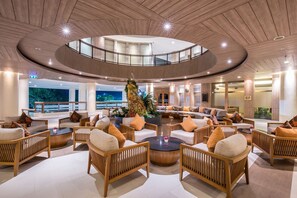 A spacious lobby with a central seating area, a circular ceiling design, and a view of the outdoors. -  Summit Windmill Golf Suite Hotel @Suvarnabhumi (Bang Phli)