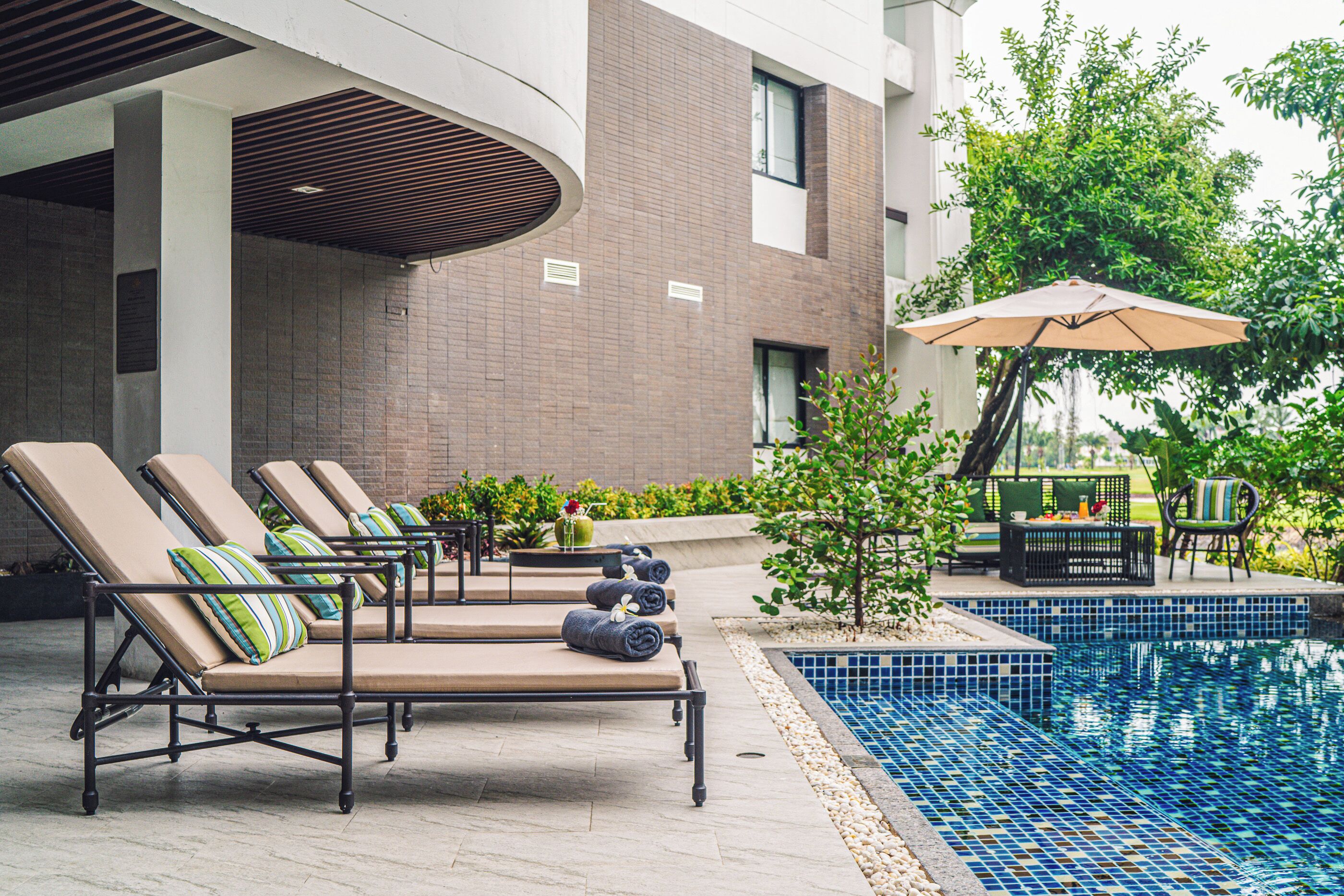 A poolside area with lounge chairs, a small pool, and a table with an umbrella.