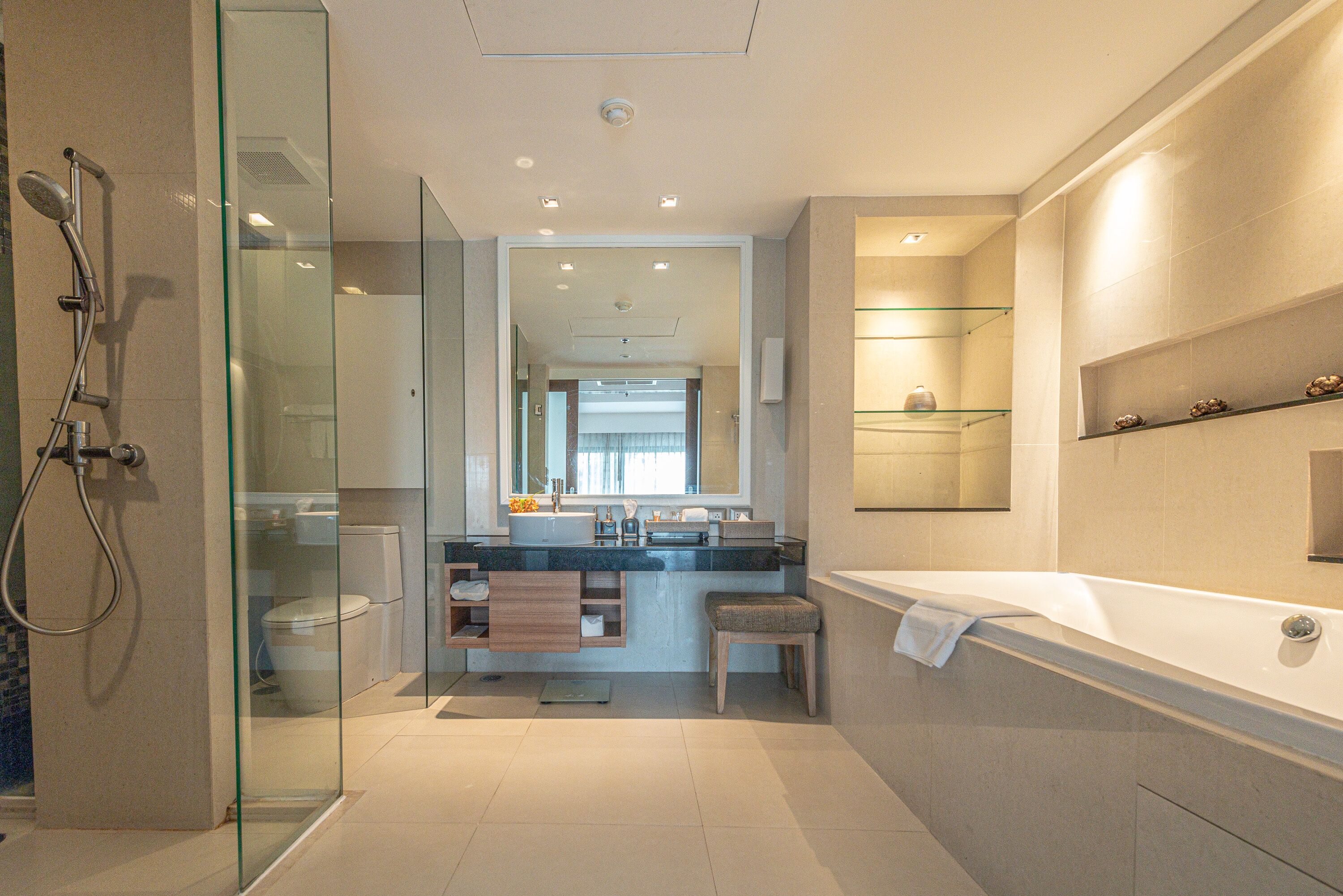 A modern bathroom with a glass-enclosed shower, a freestanding bathtub, and a vanity with a mirror.