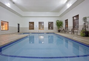 A swimming pool with tiled edges, a tiled floor, and a ceiling with recessed lighting.