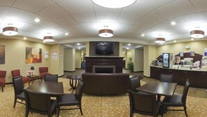 A hotel lobby with a fireplace, seating area, and a reception desk. - Holiday Inn Express Hotel & Suites Malone by IHG (Malone)