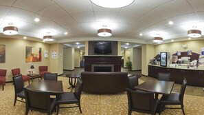 A hotel lobby with a fireplace, seating area, and a reception desk.