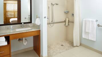 A bathroom with a sink, mirror, shower, and towel rack.