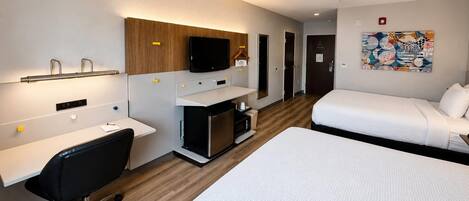 Habitación de hotel con cama, escritorio, silla y televisor.