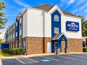 A Microtel Inn & Suites building with a brick facade, a blue entrance, and a parking lot with handicapped parking. - Microtel Inn & Suites by Wyndham Macon (Macon)