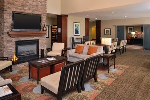 A hotel lobby with a fireplace, seating area, and a television mounted on the wall.